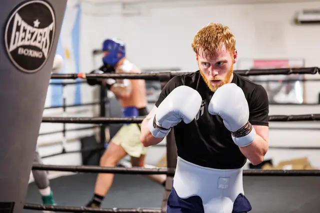 Matthew in his guard in the gym, wearing white gloves